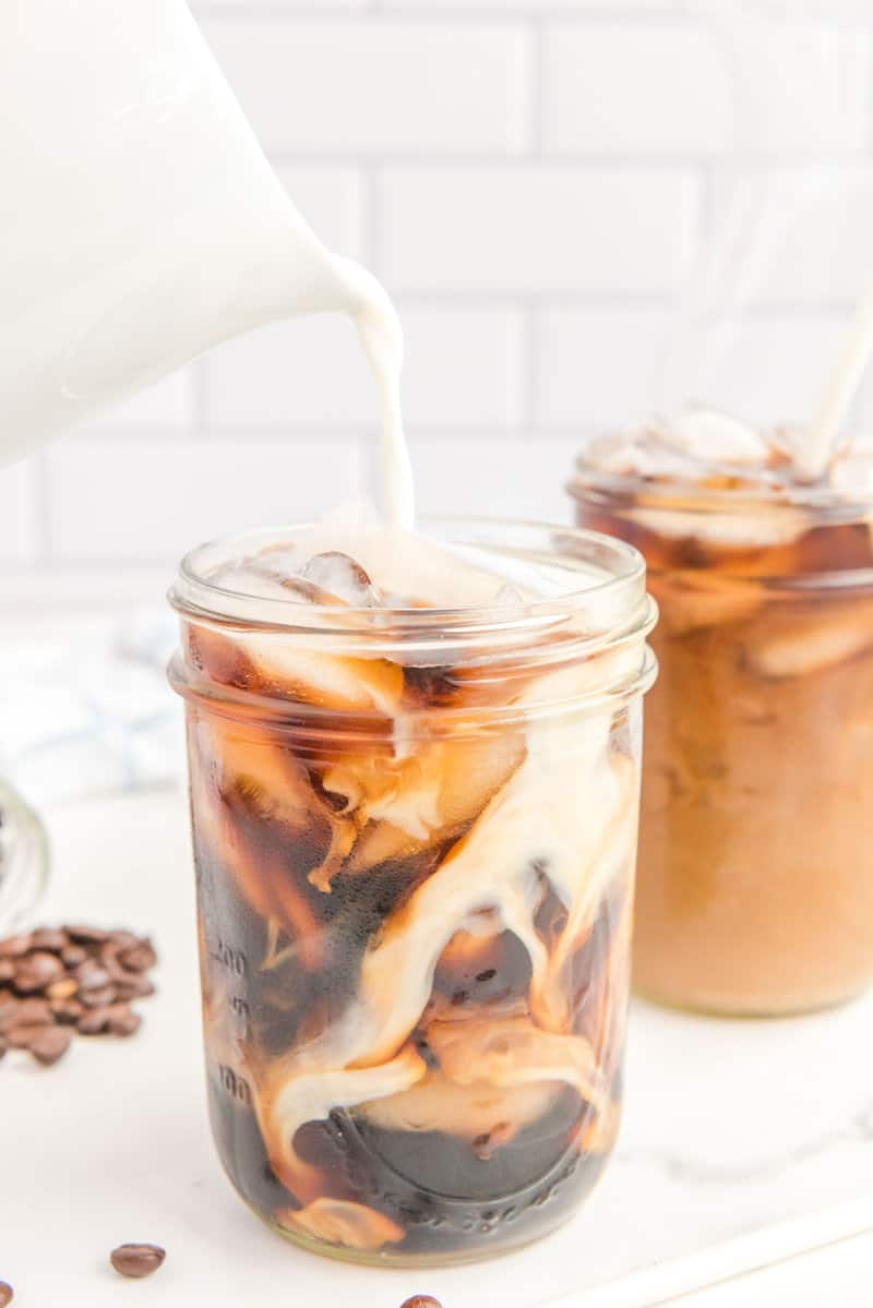 pouring cream into copycat Starbucks cold brew coffee with ice.