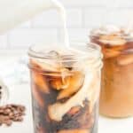 pouring cream into homemade Starbucks cold brew coffee in a mason jar.