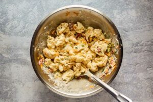 Steamed cauliflower and other ingredients in a mixing bowl.