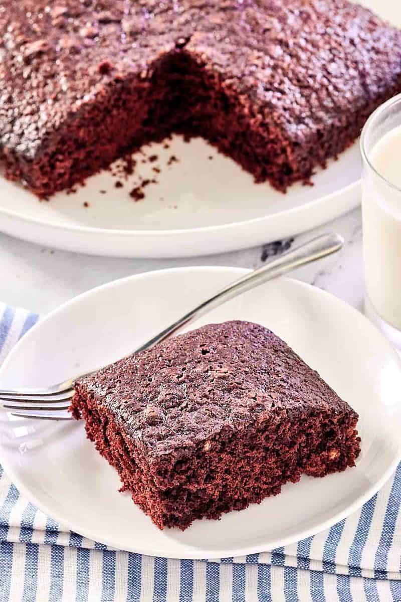 wacky cake slice on a plate with the cake behind it.