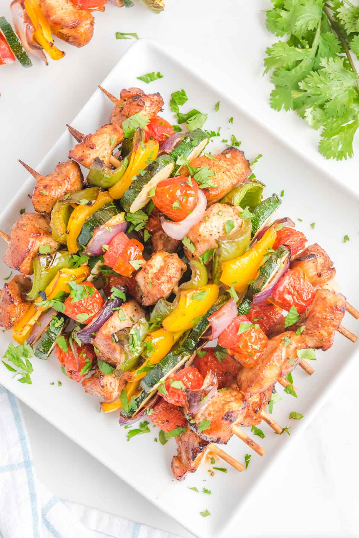 Overhead view of air fryer chicken kabobs on a square white platter.