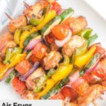 Overhead view of air fryer chicken kabobs stacked on a white plate.