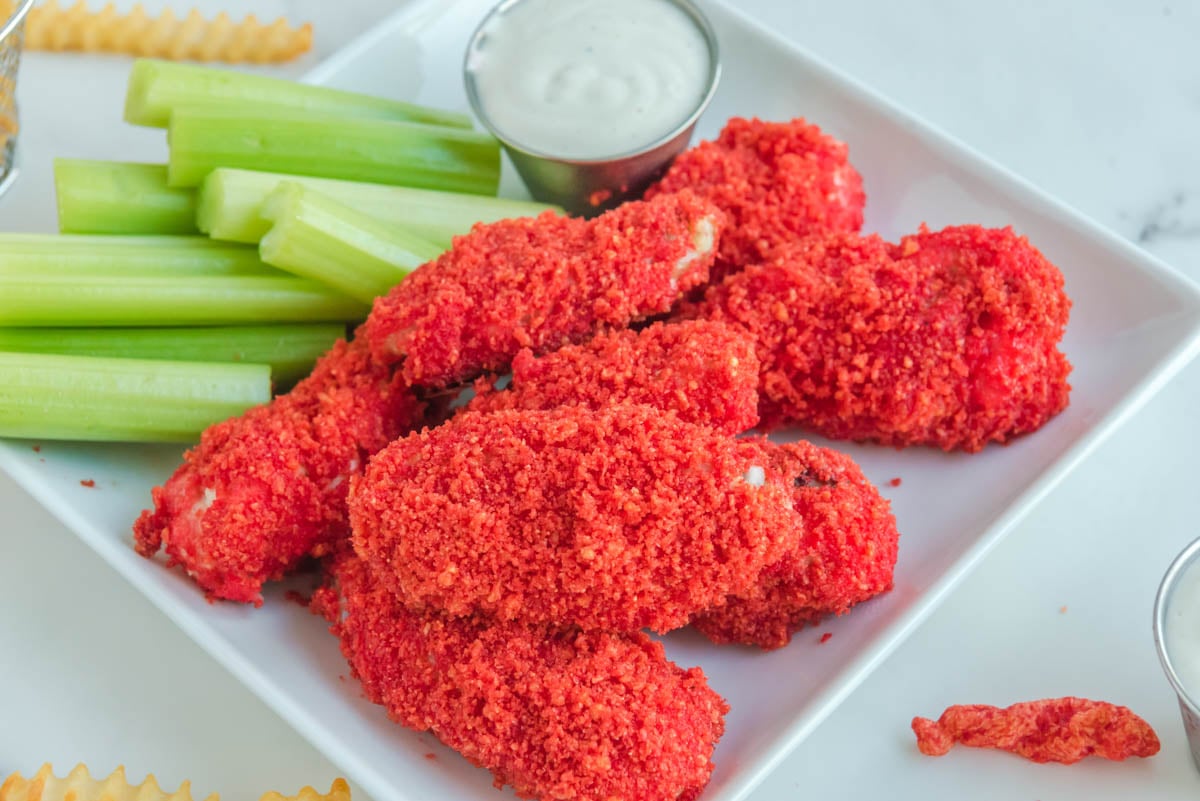 Copycat Applebee's Flamin' Hot Cheetos Wings, ranch dressing, and celery on a white plate.