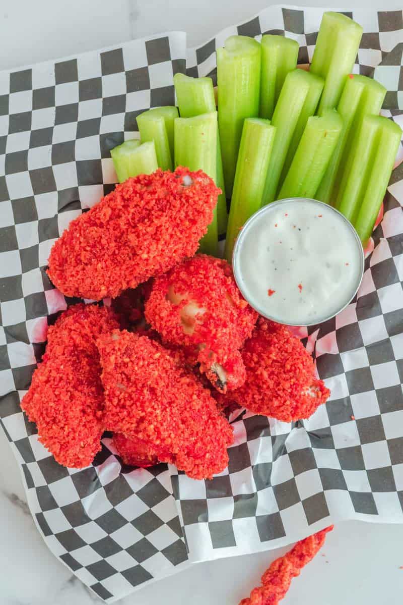 Overhead view of copycat Applebee's Flamin' Hot Cheetos Wings, ranch, and celery on parchment paper.