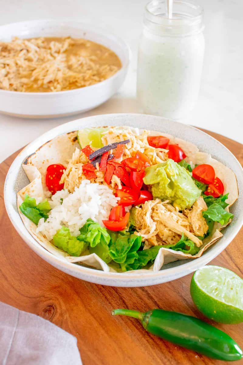 Copycat Cafe Rio shredded chicken on a salad and in a bowl.