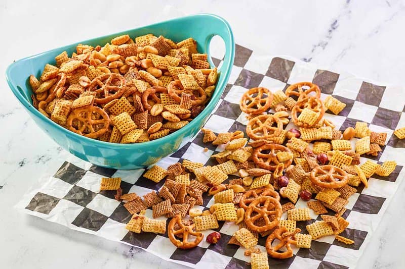 Homemade original Chex mix in a bowl and scattered on parchment.