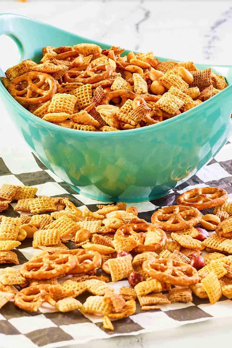 Homemade original Chex mix in a bowl and on parchment paper.