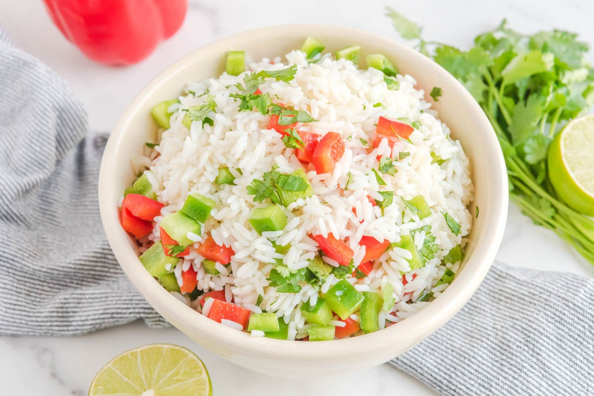 Cilantro rice in a bowl and fresh cilantro beside it.