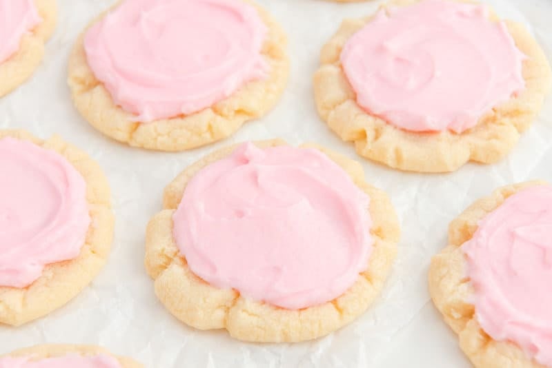 Copycat Crumbl sweetener  cookies with pinkish  frosting.