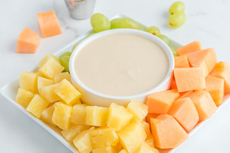 Copycat Jason's Deli fruit dip in a bowl and fresh fruit on a plate.