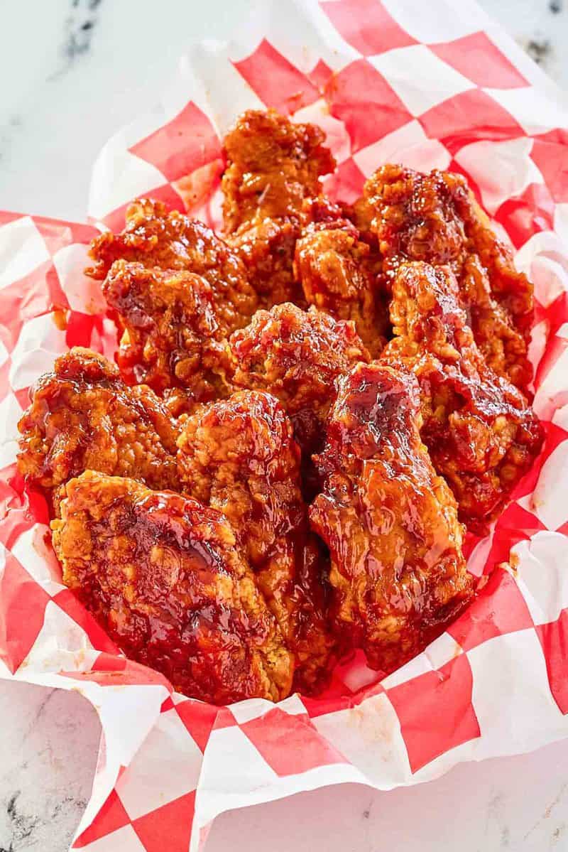 Copycat KFC honey bbq chicken wings in a parchment lined basket.
