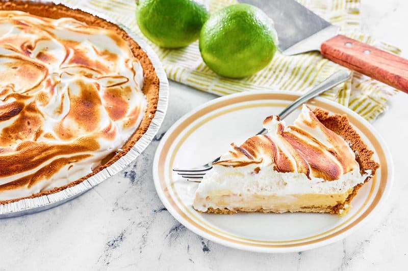 Key lime pie with meringue and a slice of the pie on a plate.