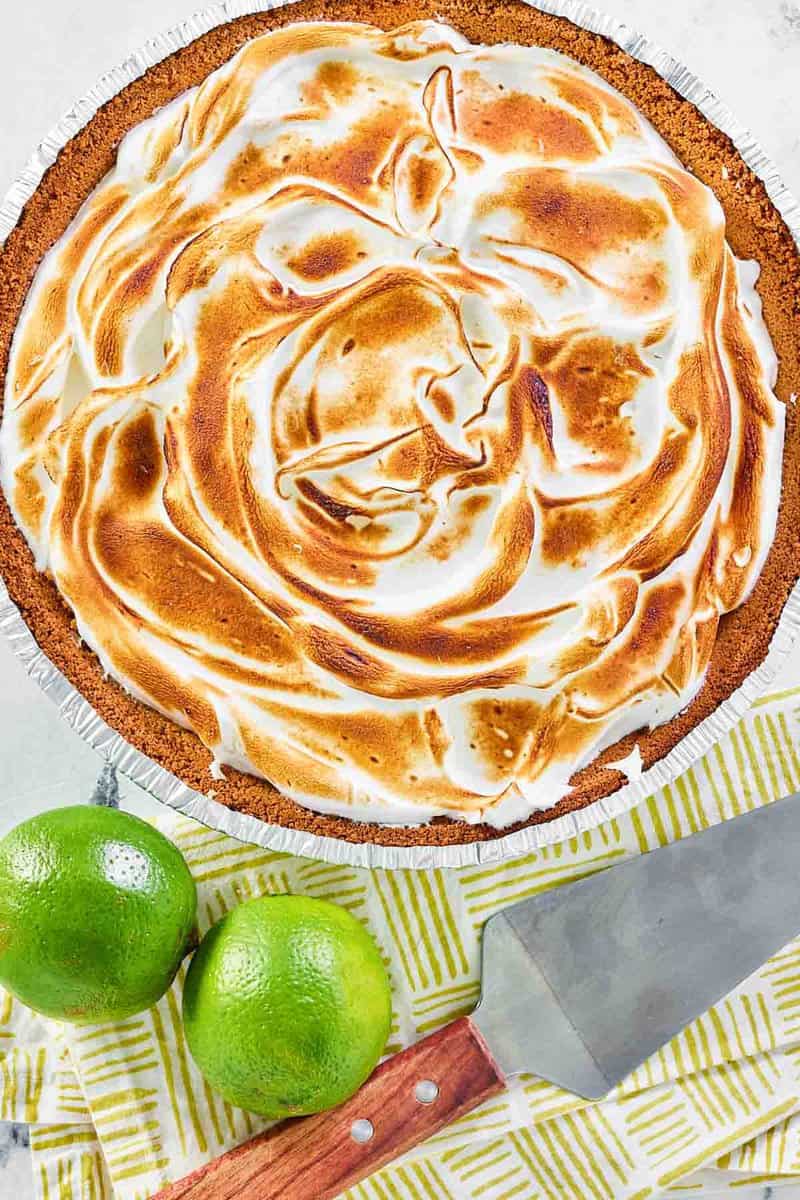 Overhead view of key lime pie with meringue and two limes.