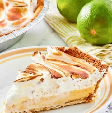 Key lime meringue pie slice on a plate and two limes.