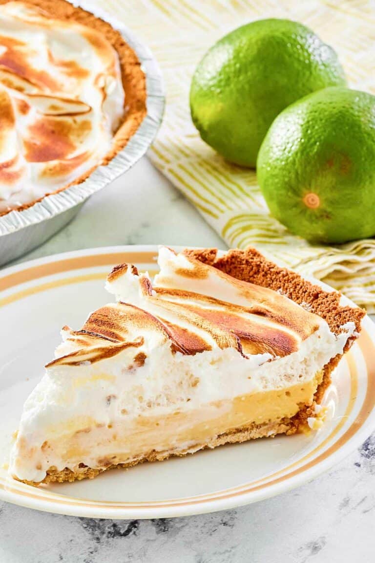 Key lime meringue pie slice on a plate and two limes.
