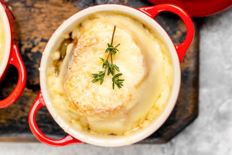 Onion soup gratinee in a crock on a wood board.