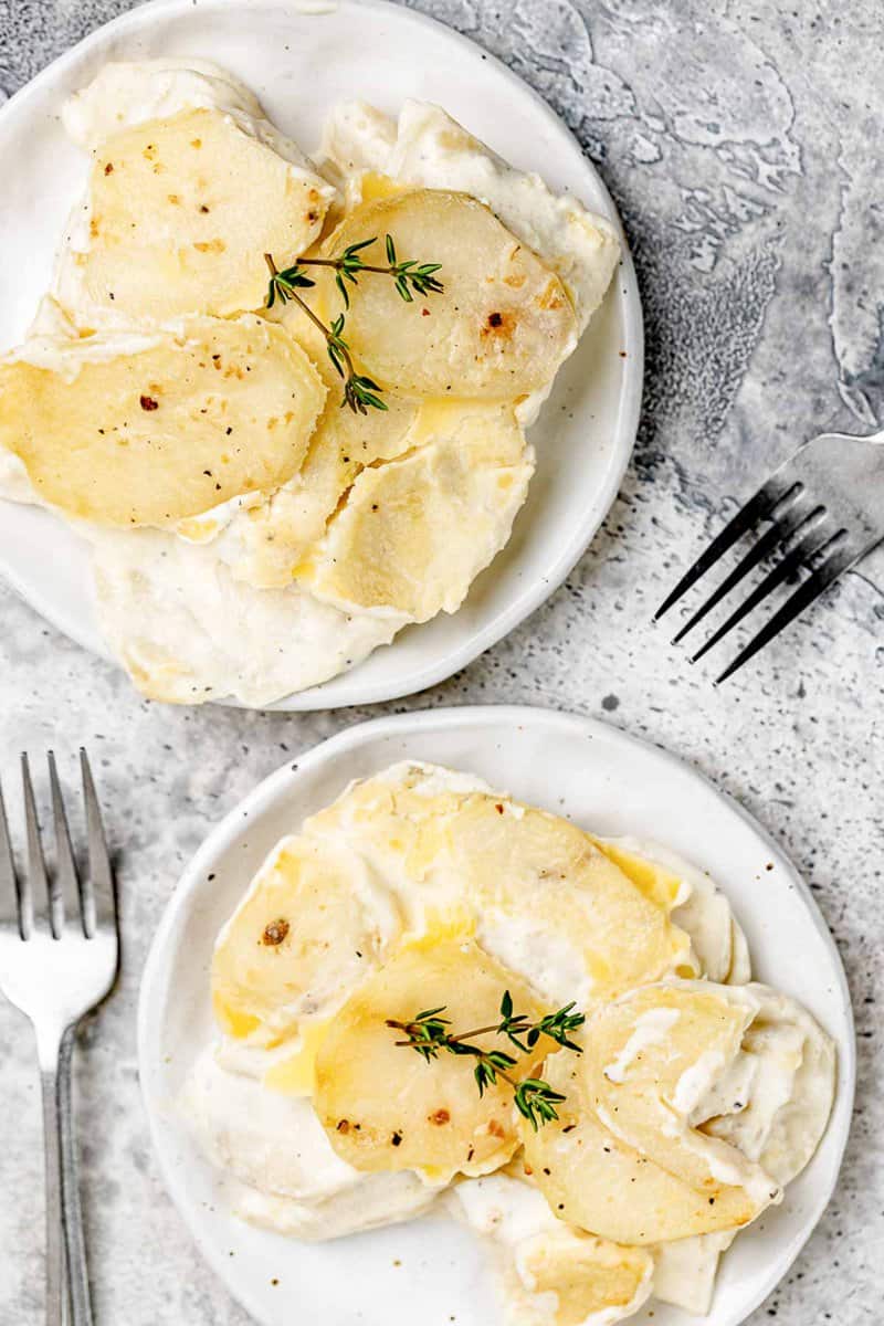 Overhead view of scalloped potatoes without cheese on two plates.