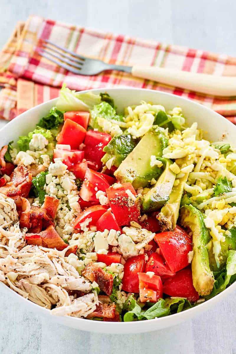 Copycat Brown Derby cobb salad in a bowl and a fork on a napkin behind it.
