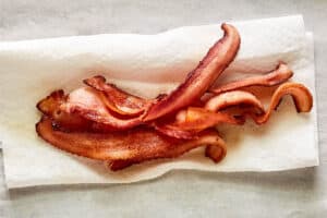 Cooked bacon strips on a paper towel.