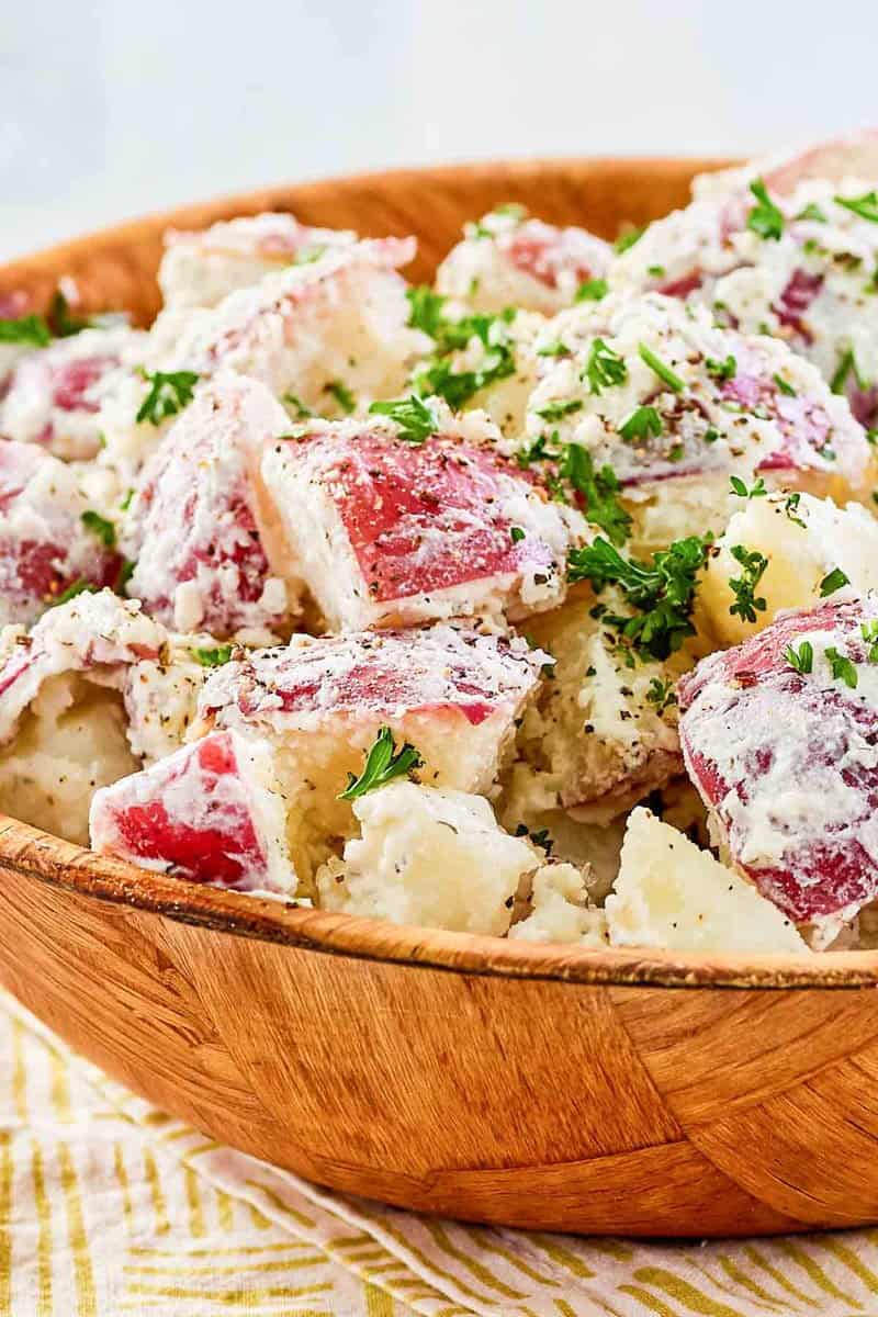 Closeup of dill potato salad in a wood bowl.