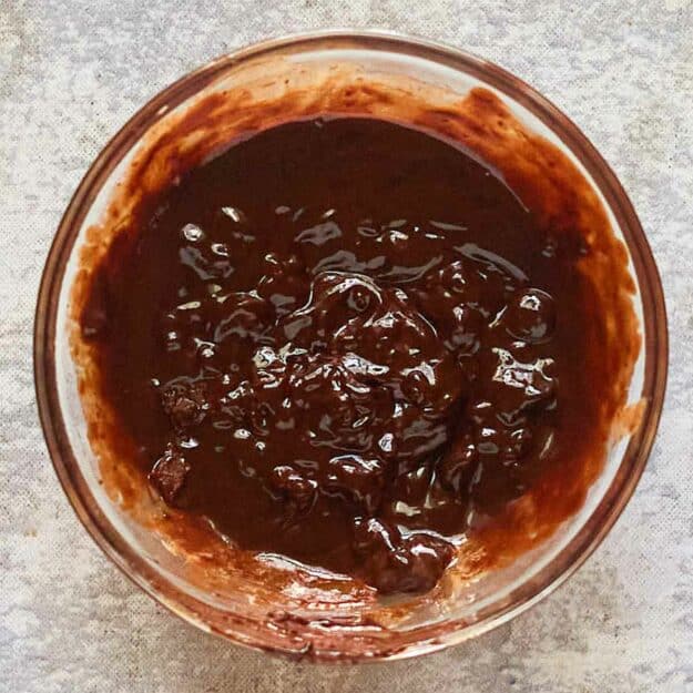 Partially melted chocolate chips and cream in a bowl.