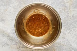 A mixture of vinegar, spices, garlic, Worcestershire sauce, and tabasco sauce in a bowl.