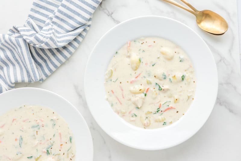 Overhead view of copycat Olive Garden chicken gnocchi soup in two bowls.