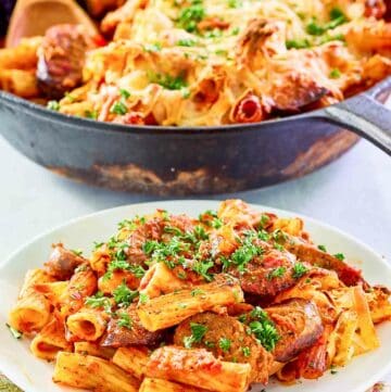 One pot sausage pasta in a skillet and a serving of it on a plate.