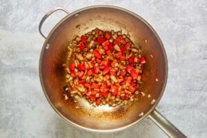 Cooking chopped bell peppers and onions in a pan.