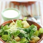 Caesar salad in a wood bowl and a bowl of copycat Outback Caesar dressing.