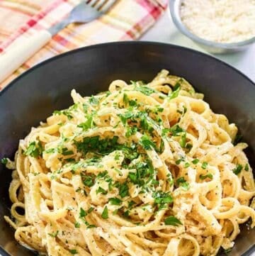 Copycat Pasta House fettuccine alfredo in a large bowl and parmesan cheese in a small bowl.