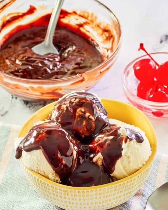 Homemade hot fudge sauce in a glass bowl and on top of ice cream.