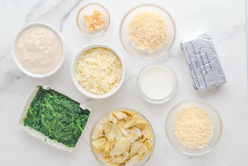 Ingredients for copycat Applebee's spinach artichoke dip connected  a marble surface.