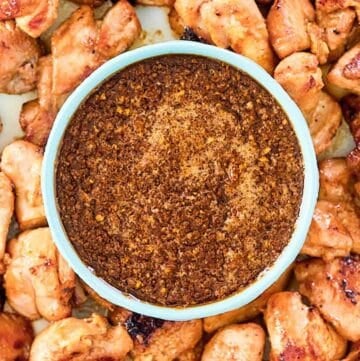 Overhead view of copycat Benihana ginger sauce in a bowl with cooked chicken pieces around it.