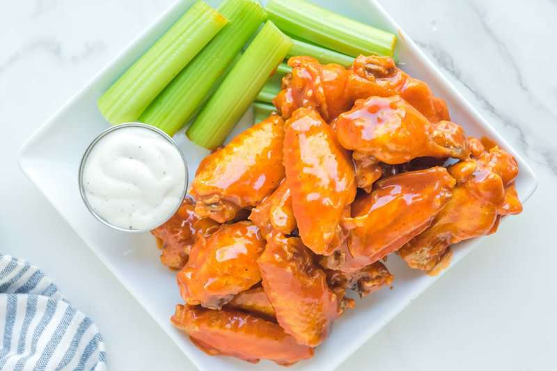 Overhead view of copycat Buffalo Wild Wings Buffalo wings, celery sticks, and dipping sauce.