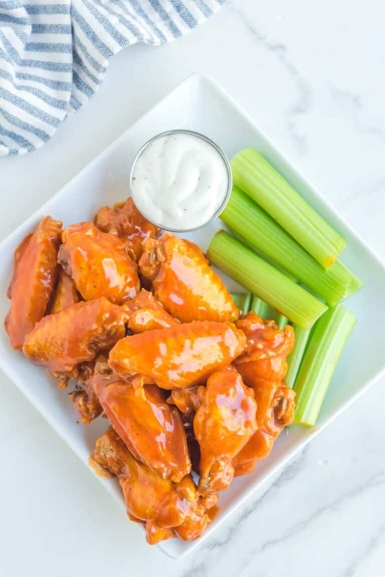 Overhead view of copycat Buffalo Wild Wings Buffalo wings, dipping sauce, and celery on a plate.