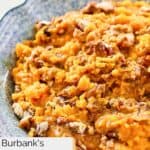 Closeup of homemade Burbank's sweet potato casserole with raisins and pecans in a blue bowl.