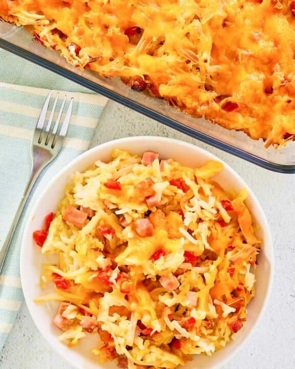 Overhead view of cheesy hash brown casserole in a baking dish and on a plate.