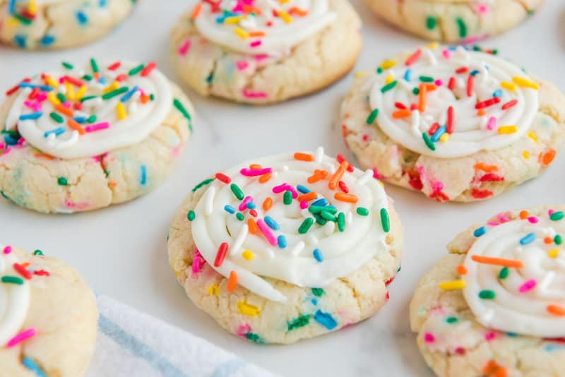 Copycat Crumbl birthday cake cookies scattered on a marble surface.