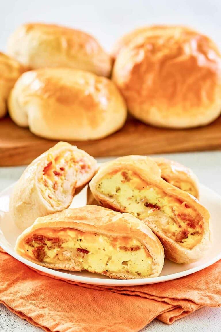 Copycat Dunkin stuffed biscuit bites with bacon on a wooden board and a plate.