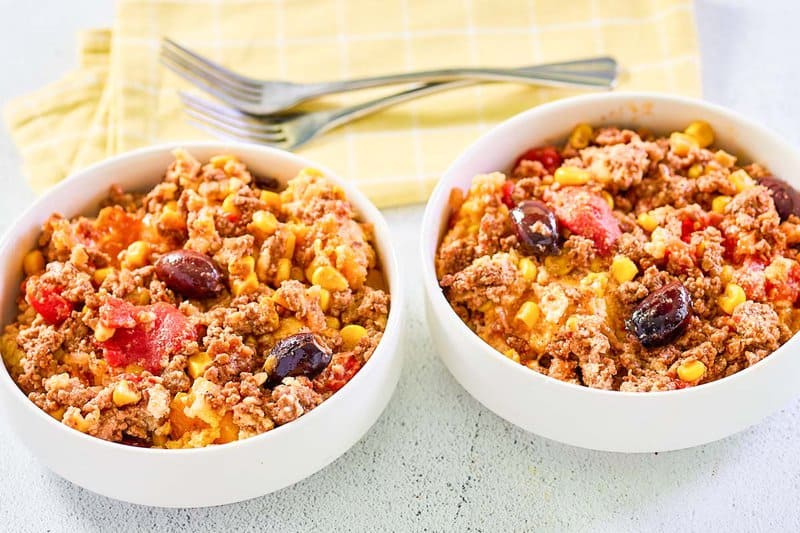 Two servings of hamburger corn casserole and two forks.