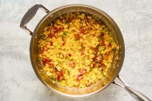 Corn, bacon, and vegetable mixture in a pan.