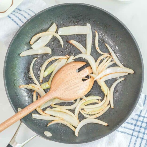Cooked sliced onions in a skillet.