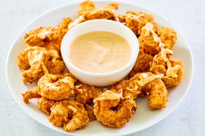 Copycat Outback bloomin fried shrimp and a bowl of dipping sauce on a plate.
