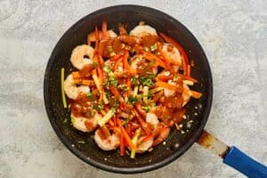 Shrimp, sauteed vegetables, and Thai sauce in a skillet.