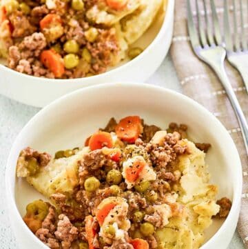 Two bowls of shepherd's pie with beef and two forks.