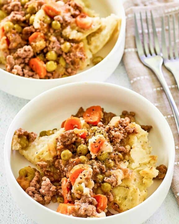 Two bowls of shepherd's pie with beef and two forks.