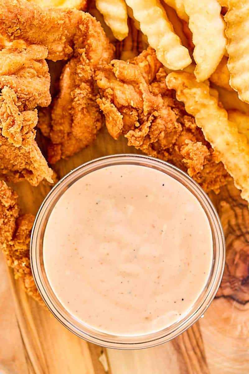 Overhead view of copycat Zaxby's zax sauce, fried chicken fingers, and crinkle fries.