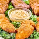 Copycat Captain Crunch chicken tenders on a platter with a bowl of Creole mustard.