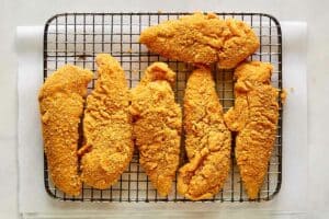 Fried Captain Crunch chicken tenders on a wire rack.